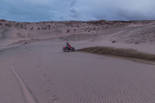 A professional motorcycle driver driving on a sandy seashore
