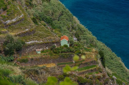An aerial shot of a small house in hills near sea