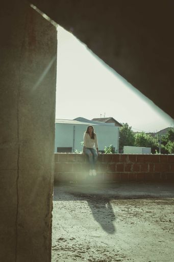 A vertical shot of a young Caucasian female sitting outdoors
