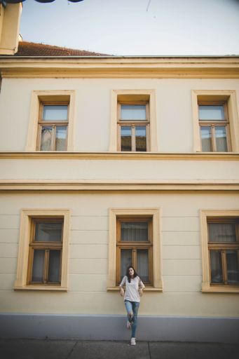 A vertical shot of a young beautiful Caucasian female leaning against the building