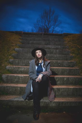 A vertical shot of a white Caucasian girl posing in a park during an evening hour