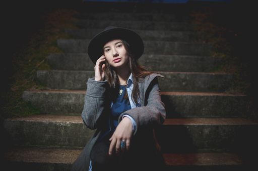 A shallow focus shot of a young beautiful Caucasian female posing while sitting on stairs