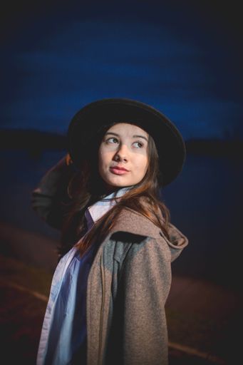 A shallow focus shot of a young beautiful Caucasian female in a black hat posing at camera