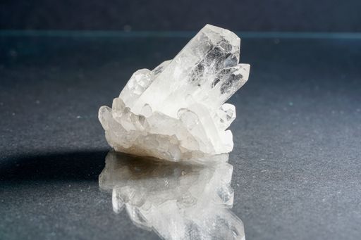A closeup shot of a shiny quartz crystal reflecting on the gray table