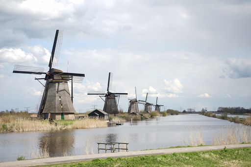 A beautiful shot of windmills near the lake against the cloudy sky background,  Kinderdijk, Netherlands