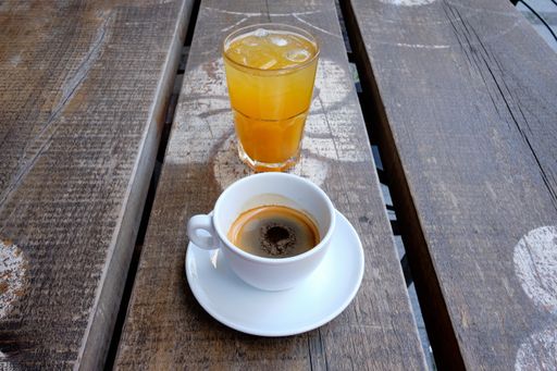 A cup of coffee and a glass of fresh orange juice on a wooden board