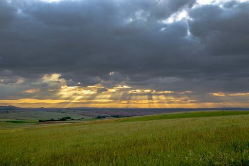 A beautiful shot of cloudy sky with sunrays from the sky across the mountain landscape during sunrise