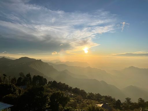 A scenic aerial view of a sunrise over a mountainous landscape with small dwellings