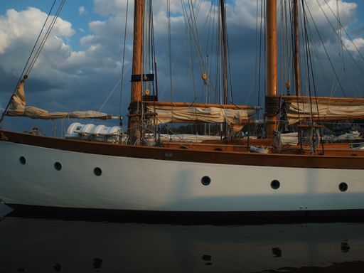 A large schooner boat floating on the water on a cloudy day