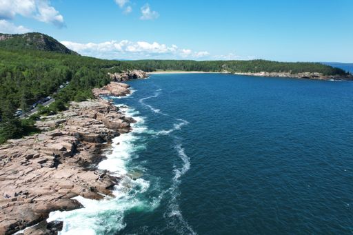 Aerial view of scenic coastline on a sunny day with lush green trees in the foreground