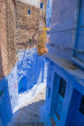 A narrow empty street with blue buildings in the old town medina of the city of Chefchaouen, Morocco