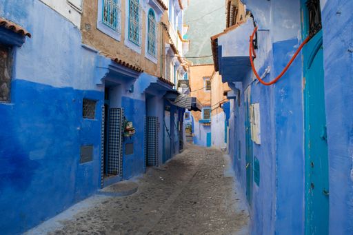 A narrow empty street with blue buildings in the old town medina of the city of Chefchaouen, Morocco