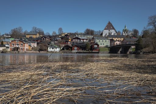 A view of a small rural village with a landscape featuring a small body of water surrounded by lush vegetation and a number of historic buildings