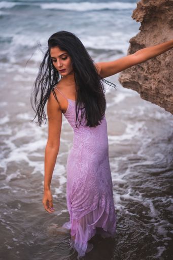 A young brunette Caucasian woman in a purple dress posing in the water in Cabo de Gata beach, Spain