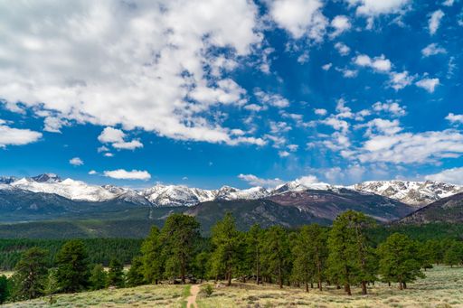 A stunning view of Rocky Mountain National Park in Colorado with vibrant foliage in the foreground and snow capped peaks in the background