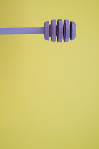 A vertical shot of a purple honey dipper isolated on yellow background for a copy space