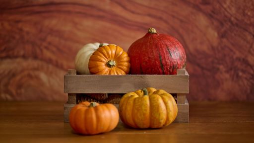 A collection of vibrant orange pumpkins is displayed against a backdrop of luxurious, ornate detailing