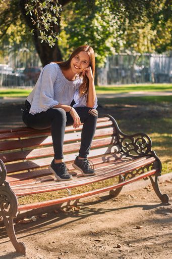 A beautiful shot of a girl in a blue shirt sitting on the bench