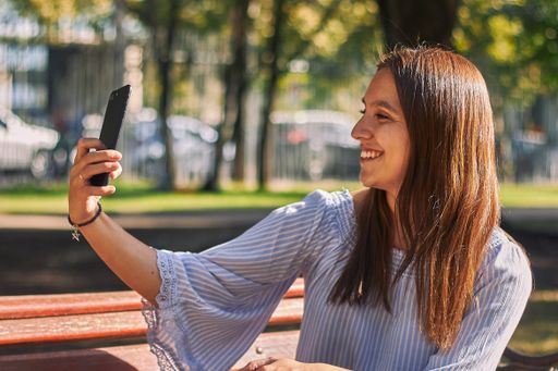 A vertical shot of a girl in a blue shirt taking a selfie