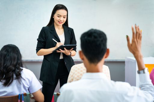 A Southeast Asian woman reading a lecture in a classroom