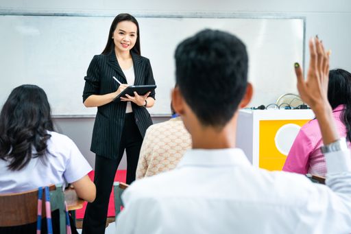 A Southeast Asian woman reading a lecture in a classroom