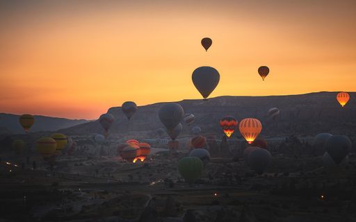 The mesmerizing view of hot air balloons in the rocky mountains of Kapadokya, Turkey during sunset