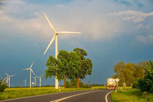 A scenic view of a farm with wind turbines beside a country road in Lower Saxony, Germany