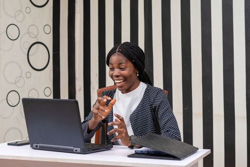 A young Nigerian woman looking at her laptop happily after getting a job