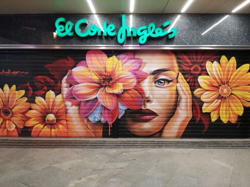 Madrid, Spain; April 25, 2021: Graffiti of a white woman with red lips and a large colorful flower on the door of a Corte Ingles shopping center in