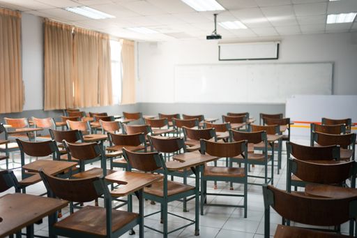 A classroom with a variety of chairs set against the backdrop of windows and a blackboard