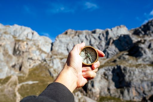 A selective focus shot of a person holding a compass with a blurred background