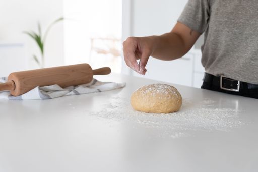 a young woman placing flour to homemade dough