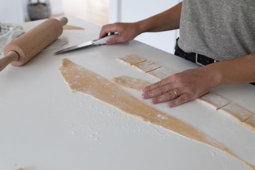 a young woman cutting pasta for food at home