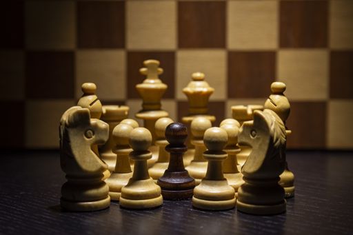 The white chess pieces surround a black pawn with a chessboard background
