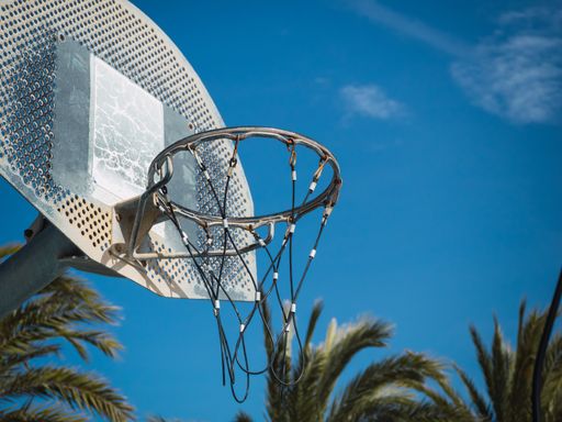 A low angle shot of a basketball hoop under the blue sunny sky