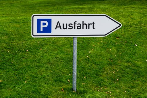 Road sign entrance to the parking lot with a lawn as a background.