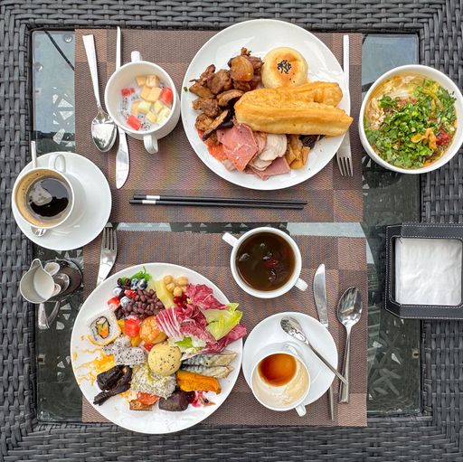 A picturesque breakfast setting featuring a wooden outdoor table adorned with cups, plates, and other serving items