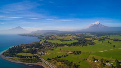 A stunning aerial view of the Calbuco volcano erupting around a small town near the coast