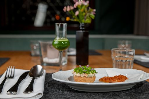 An appetizer arrangement of a sourdough bun, spring onion, and a heart-shaped waffle
