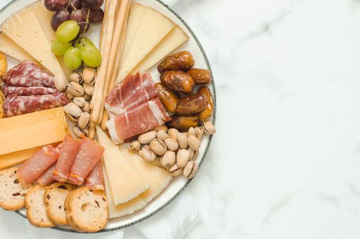 Cheese board brunch for a party with pistachios, olives, grapes and dates