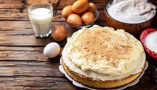 Freshly baked cake on a rustic kitchen table with various ingredients