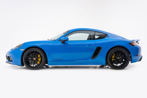 Side view of a blue porsche 718 Cayman GTS in a white background, black wheels, sports coupe car