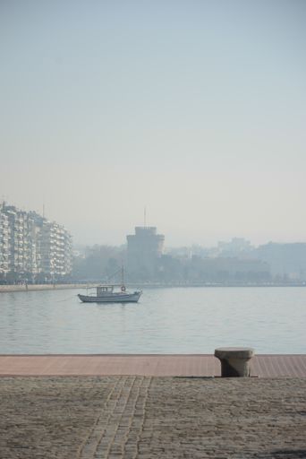 The beautiful shot of the boat in a lake surrounded by old buildings on a foggy day