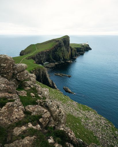 The Neist Point Lighthouse on Scotland's rocky coastline surrounded by lush green vegetation