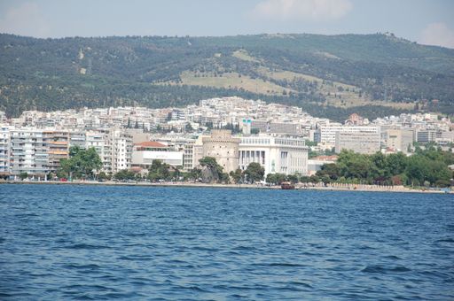 The beautiful shot of the city with white buildings behind the lake with mountains in the background