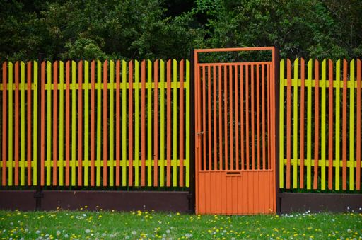 A closeup shot of a colorful fence and orange door, yellow and orange pettern