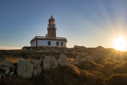 The Corrubedo lighthouse surrounded by rocks and grass under the sunlight in Spain