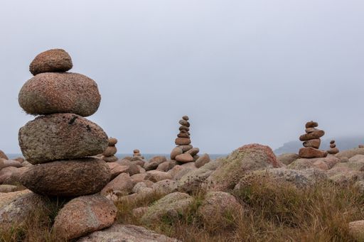 The stones on top of each other surrounded by grass in a field under a cloudy sky