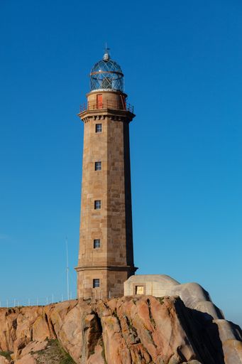 A vertical picture of the Lighthouse of Cabo Vilan in the rocks under the sunlight in Spain
