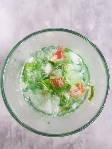 A top view of cup of cocktail with ice and mint leaves